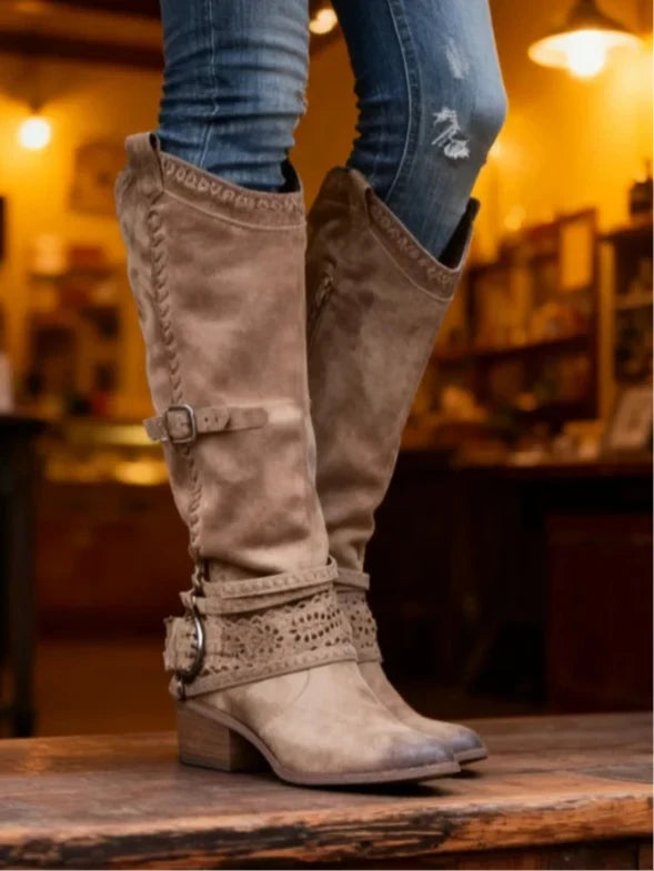 Bottes hautes taupe à boucle vues de côté, portées avec un jean dans un café