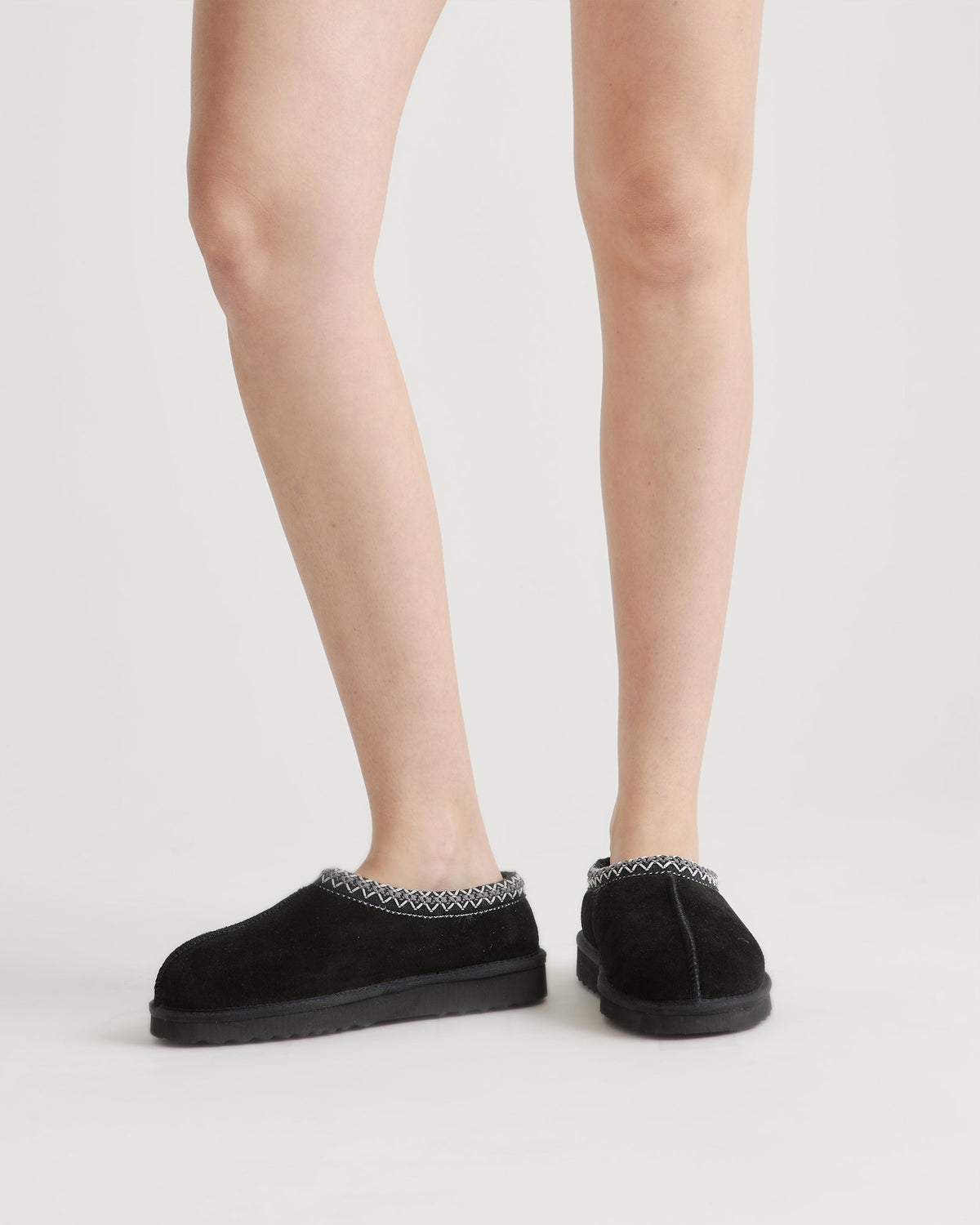 Pantoufles-sabots noires portées, vue des jambes