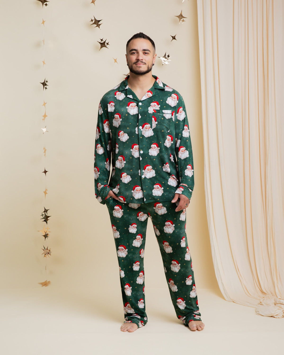 Homme en pyjama de Noël à motif de Père Noël devant un rideau, vue de face