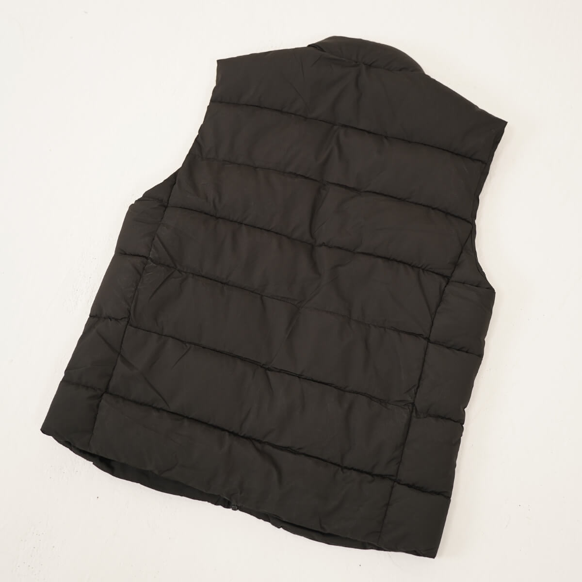 Veste chauffante sans manches noire, vue de dos posée à plat